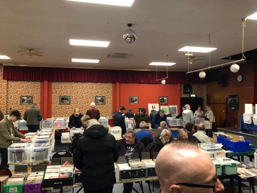 Stalls at a record fair with people milling around and crate-digging